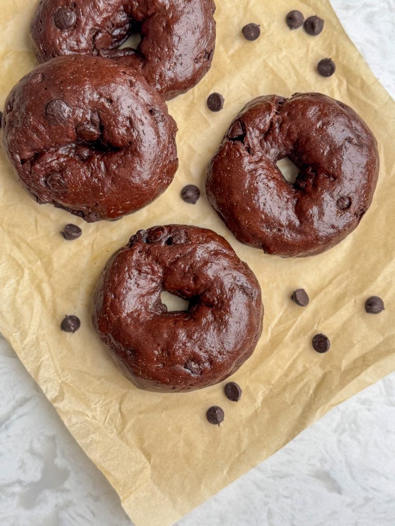 High protein chocolate bagels on brown parchment with chocolate chips.